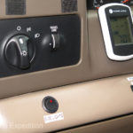 On the lower dash, left to right on the left hand side of the steering column: A switch for the side flood lights on the rack over the cab, a fuel tank selector switch, and a inside/outside temperature gauge.